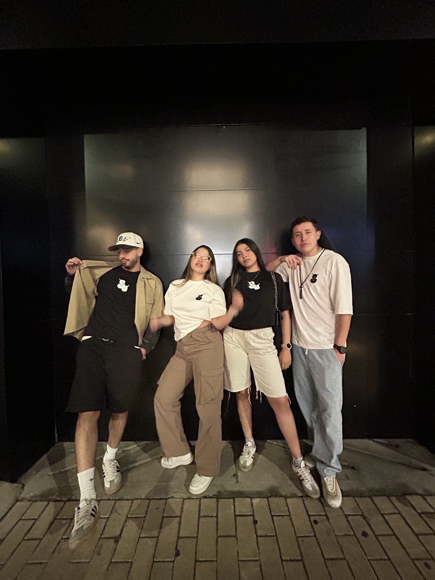 Cuatro personas frente a una pared negra con las camisetas Intrinsic