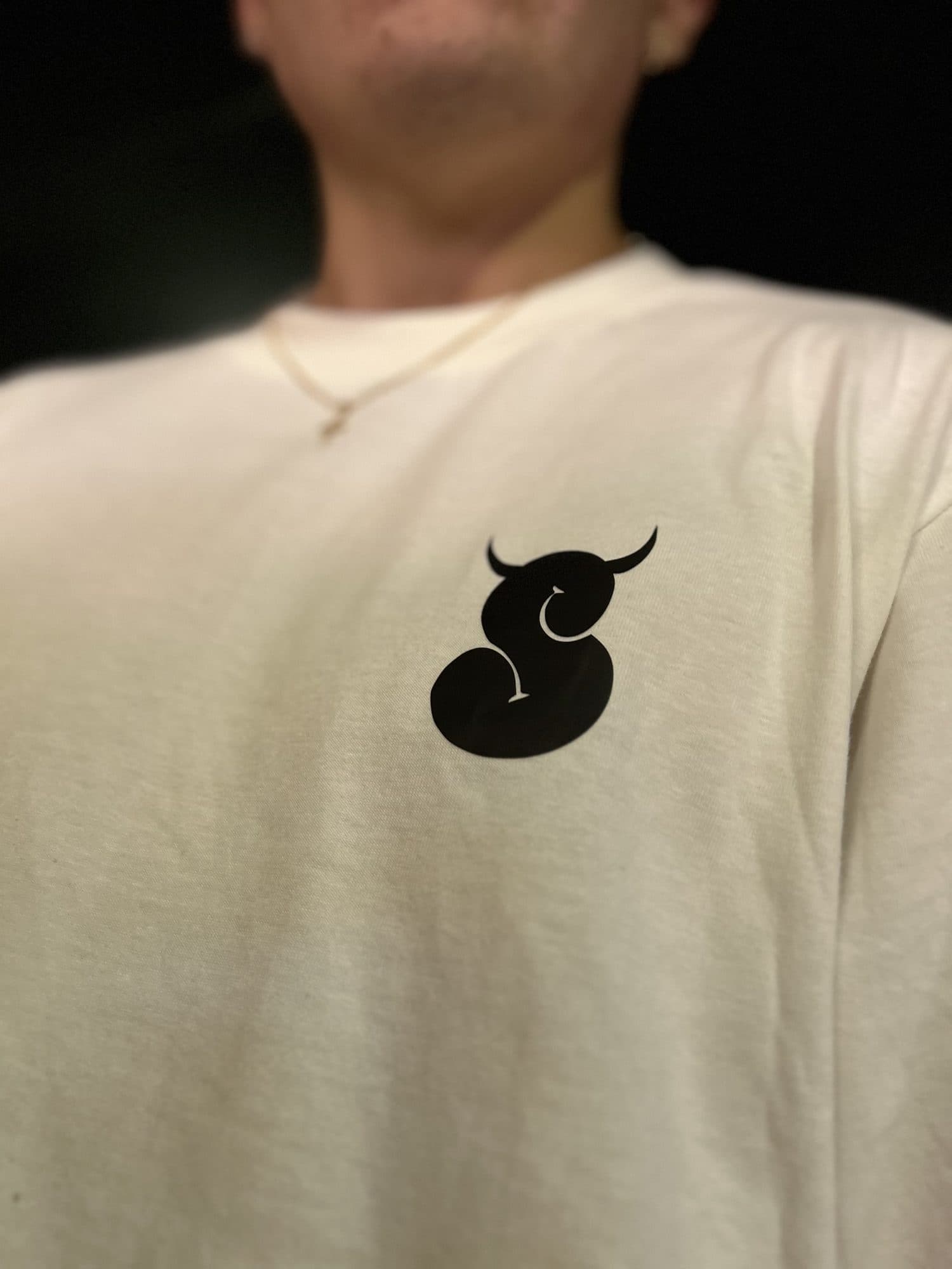 Detalle del logo S negro al pecho de la camiseta Intrinsic blanca