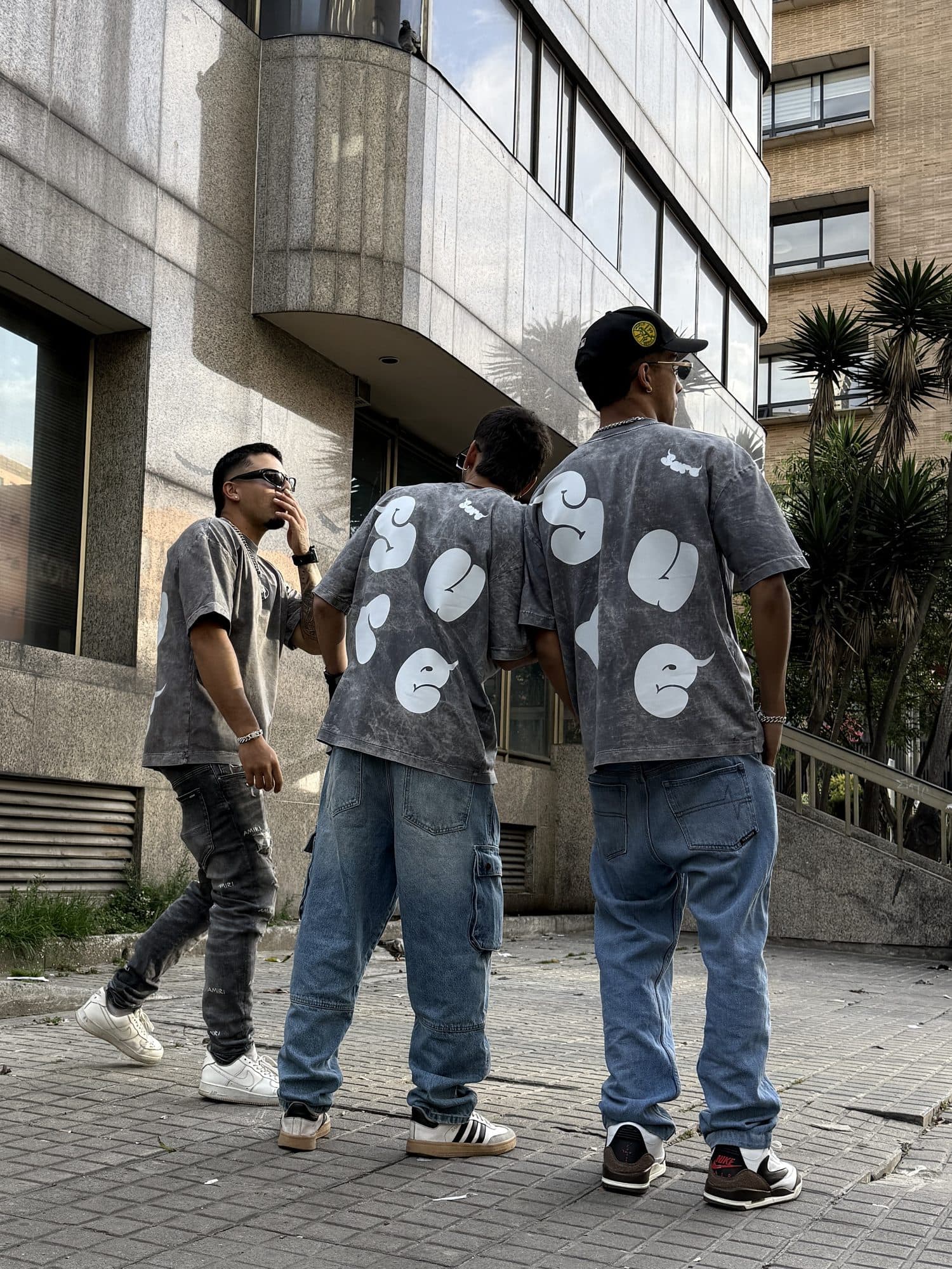 Tres personas de espaldas con las camisetas Niebla y las letras SURE infladas