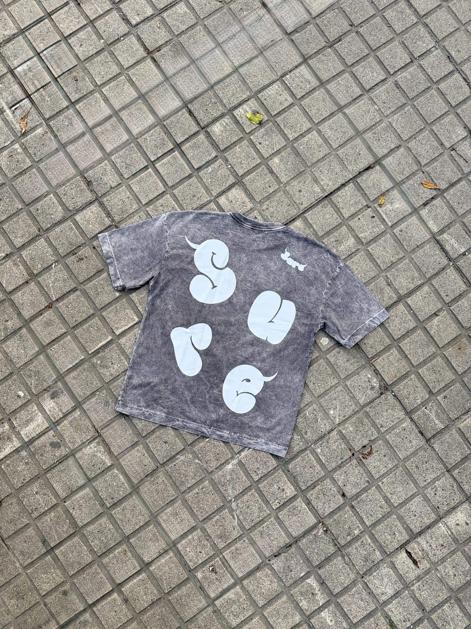 Camiseta Niebla gris sobre el piso, vista de espalda con las letras SURE
