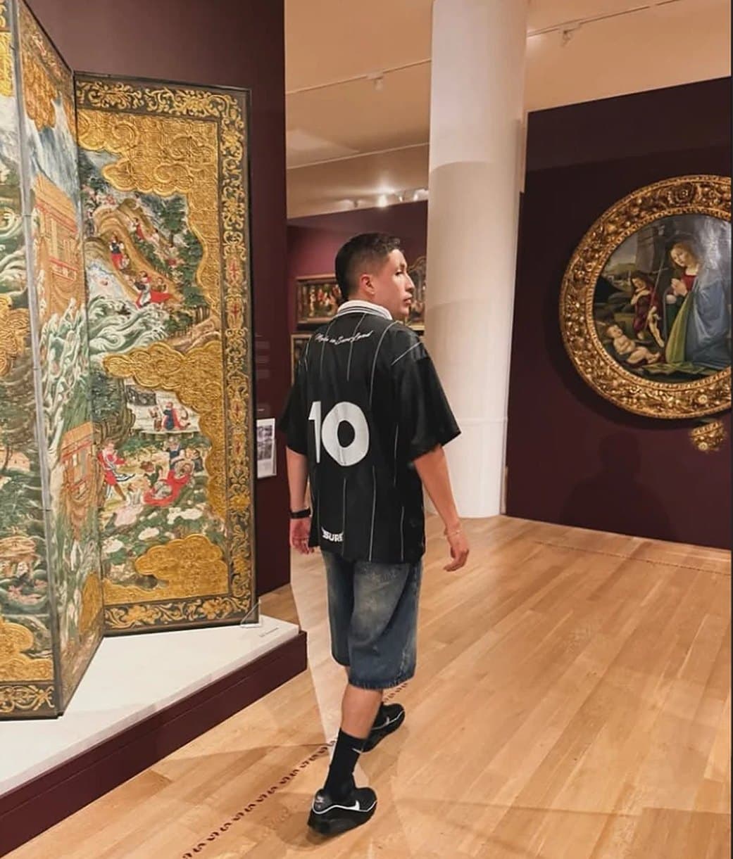 Modelo de espaldas en un museo con la camiseta Sure26 y el número 10