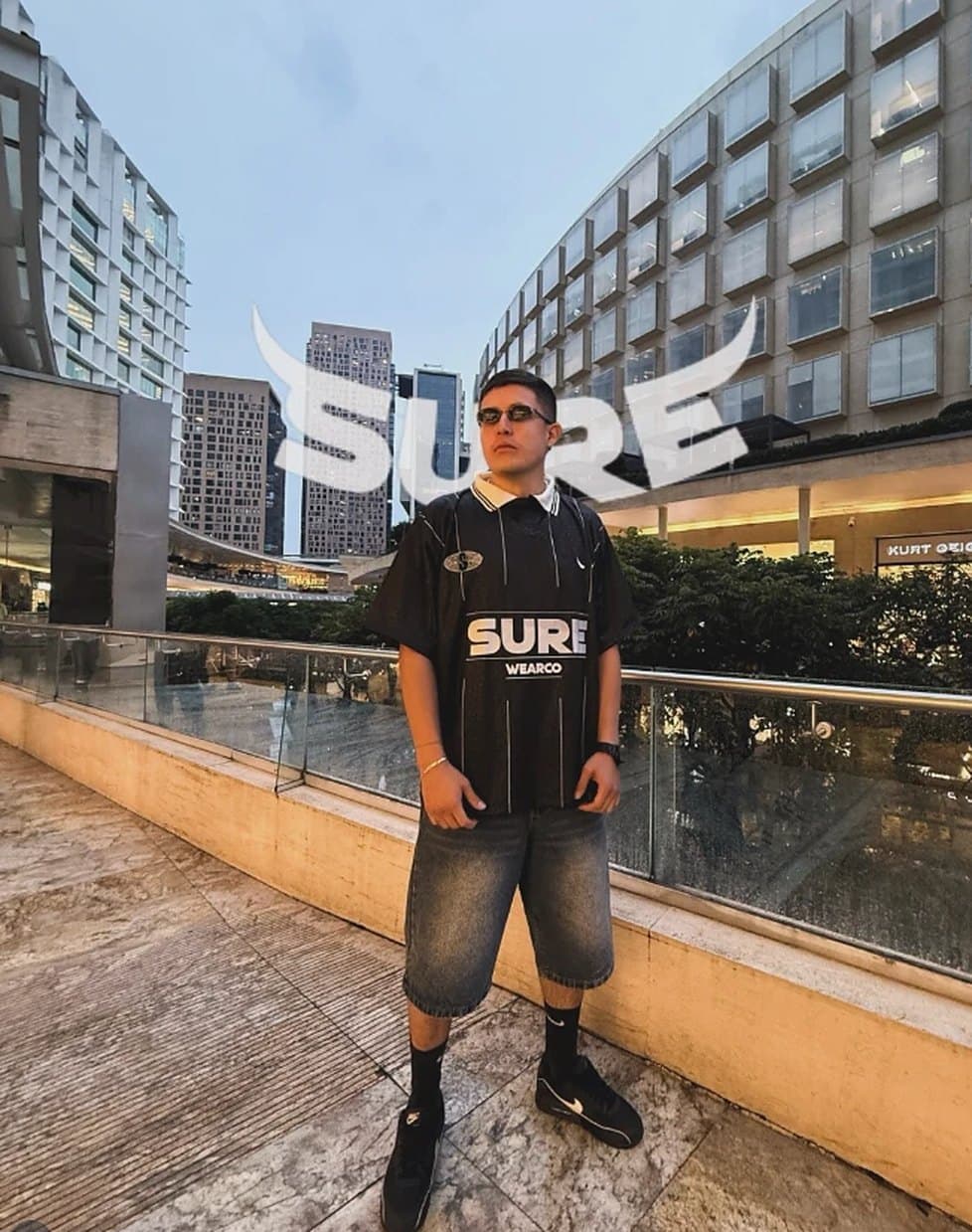 Modelo de cuerpo entero con la camiseta Sure26 en una terraza