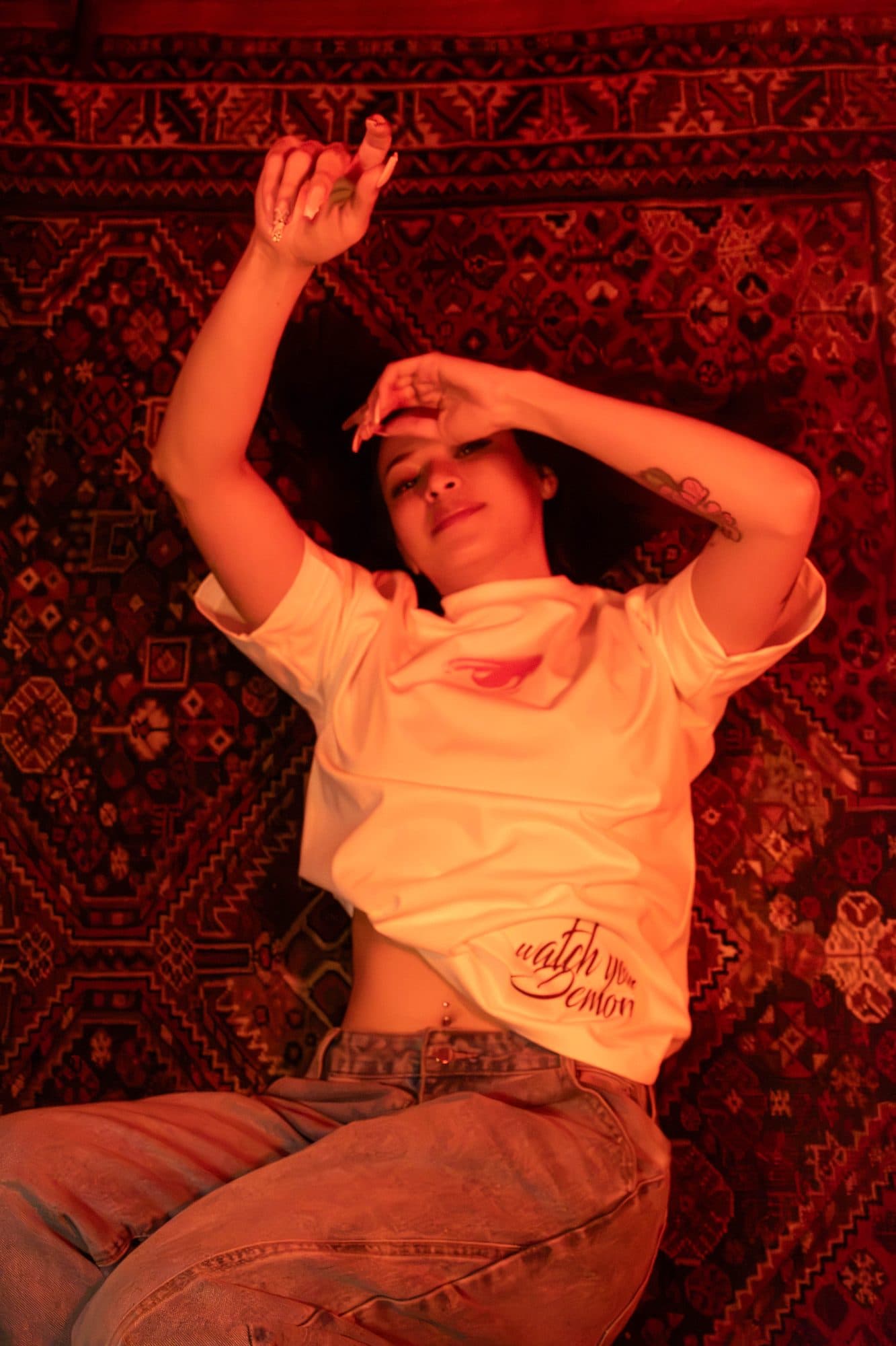 Modelo acostada sobre una alfombra con la camiseta Disidencia