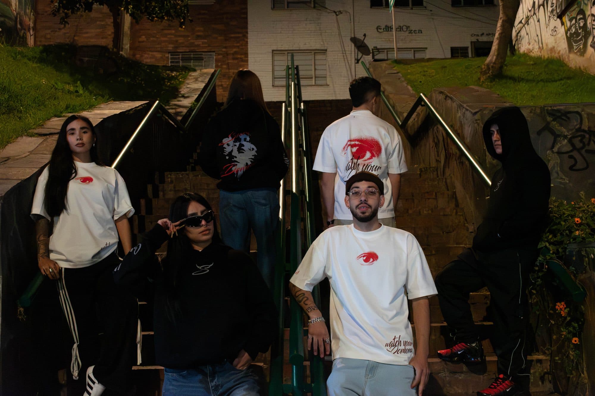 Grupo en una escalera de noche con camisetas y hoodies Disidencia