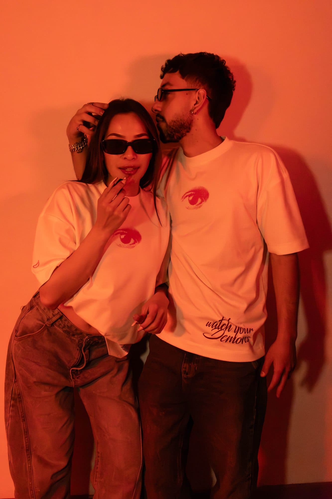 Pareja con camisetas Disidencia frente a una pared naranja
