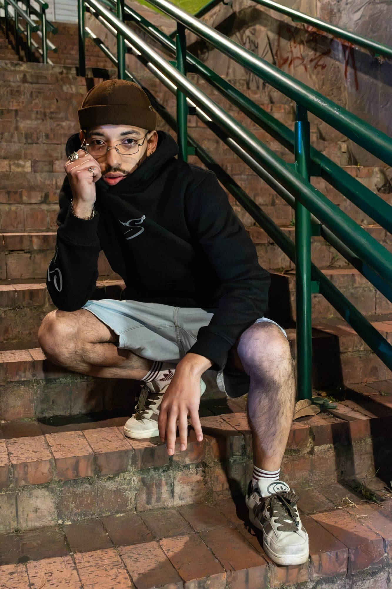 Modelo en una escalera de ladrillo con el hoodie Disidencia negro