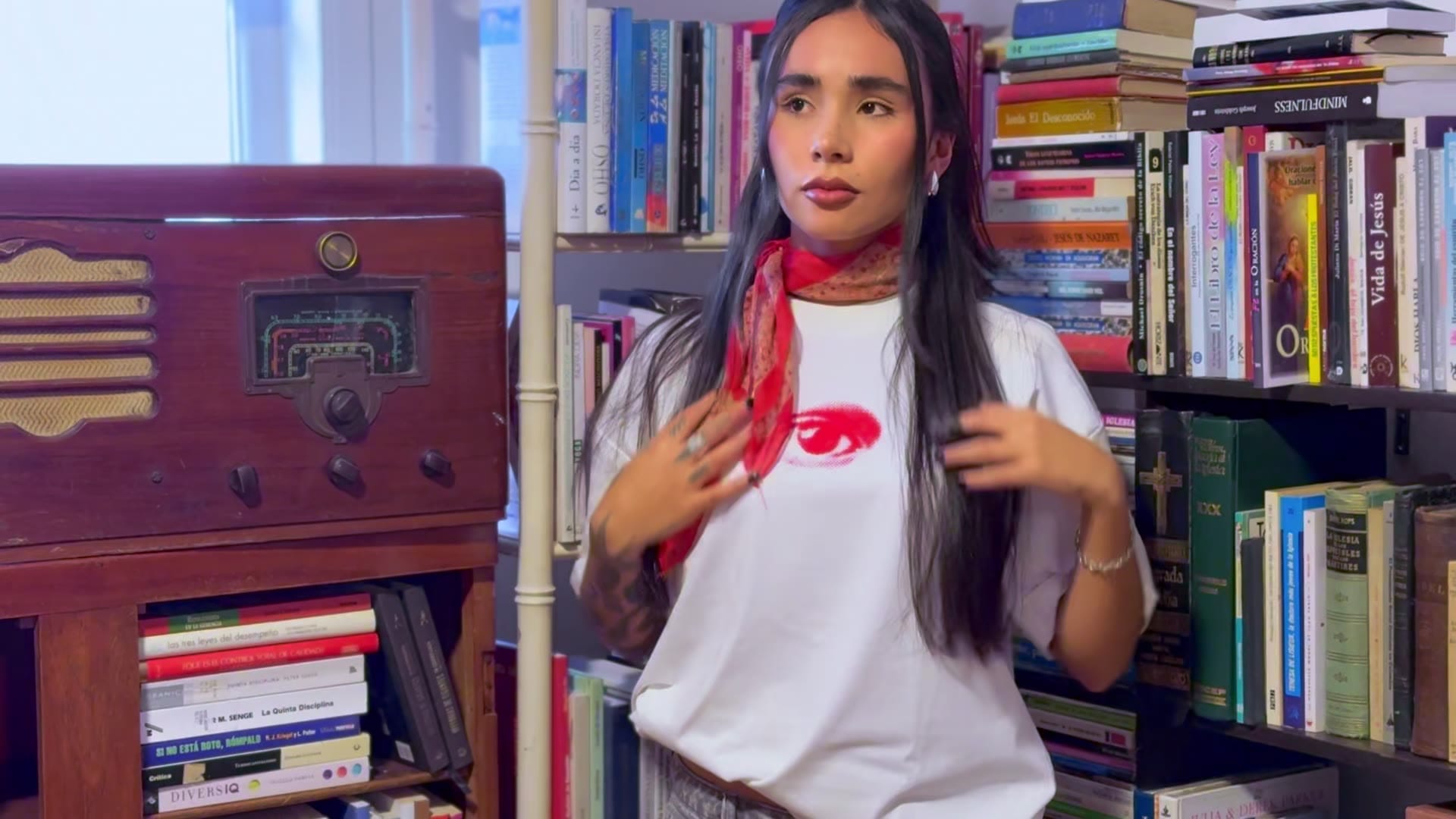 Modelo con la camiseta Disidencia blanca y una pañoleta roja en una librería