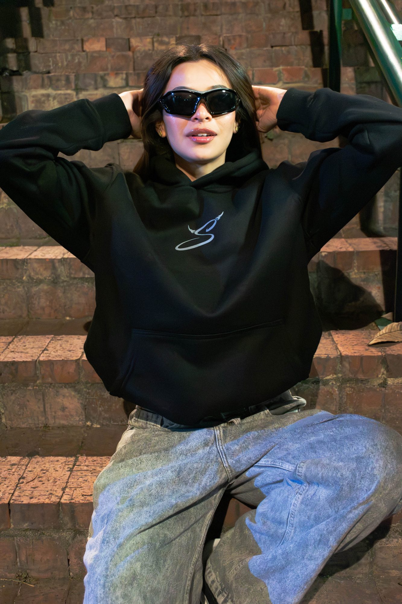 Modelo de frente con el hoodie Disidencia negro y el monograma S al pecho