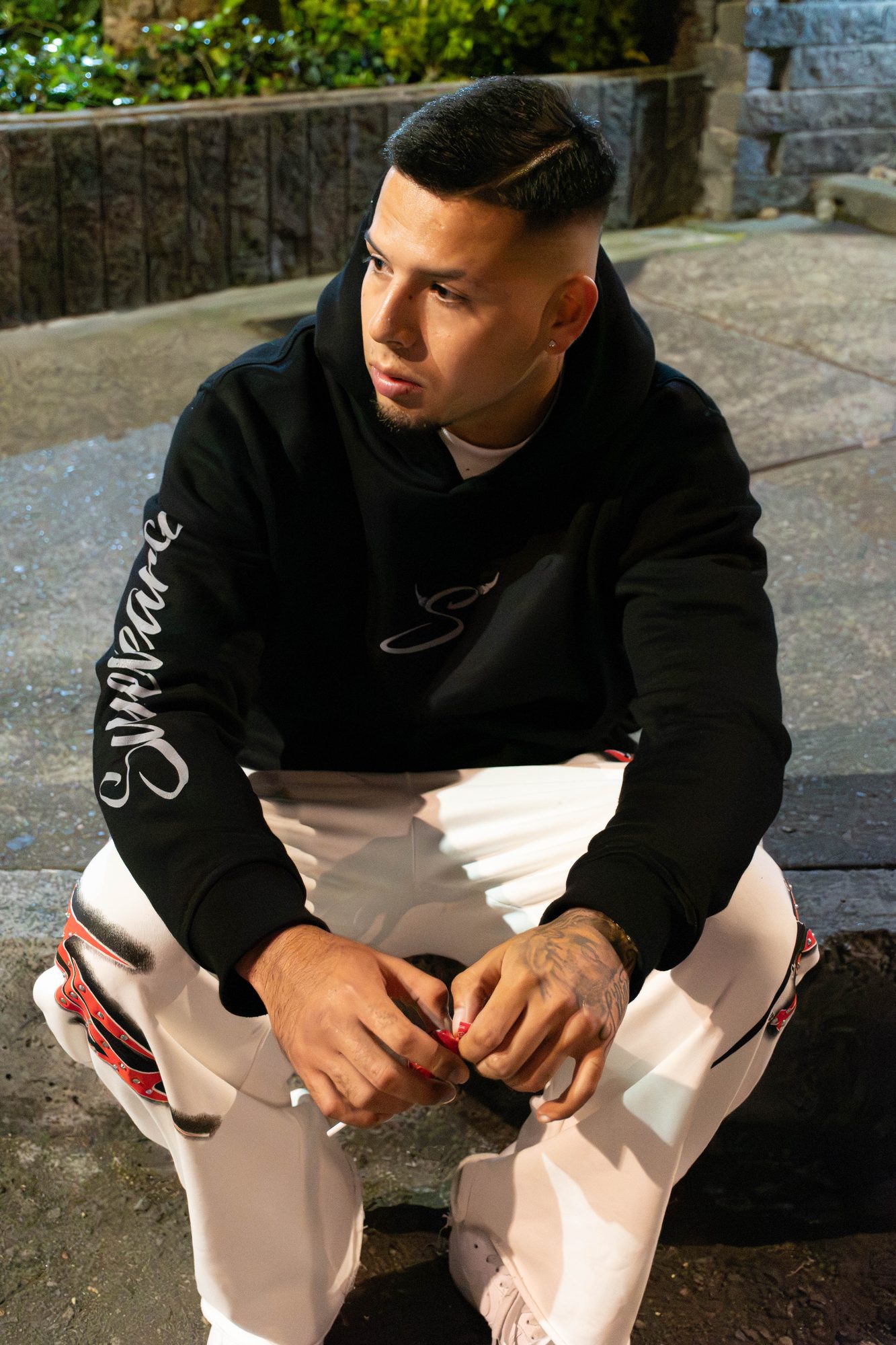Modelo agachado con el hoodie Disidencia; se ve la manga estampada